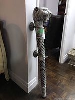 Full-length view of the painted metal ceremonial mace standing upright against a wall.