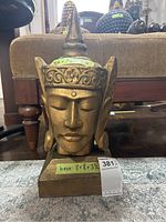 Front view of Indonesian style wooden bust showing facial features, pointed hat, and floral carvings on headdress. Dimensions marked as 8.5 x 7.5 x 15 inches.