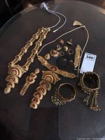Full set of 16 pieces ornate costume jewellery laid out including necklaces, earrings, rings, bangles