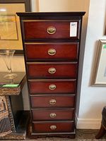 Front view of tall lingerie dresser with seven drawers and brass handles.