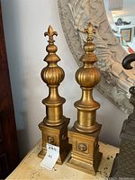 Pair of brass finials side by side showing full height and base details.