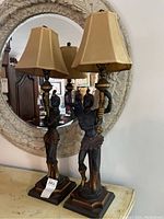 Front view of both Nubian-style figure lamps with matching shades in front of mirror