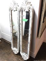 Pair of mirrors leaning against wall showing full frames and glass.