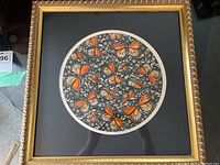 Framed round watercolor print of monarch butterflies with a gold decorative frame and black matting.
