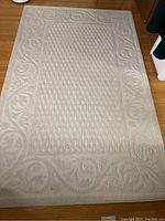 Full view of beige area rug laid flat on wood floor showing overall pattern and dimensions.