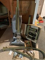 Full view of Kirby Dual Sanitronic 80 vacuum with attached bag, flexible hose, and boxed accessories including various nozzles and wands, placed on floor.