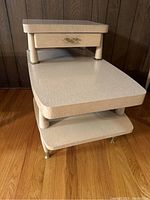 Side angle of the blonde wood MCM end table showing two-tier step design and drawer beneath top tier.