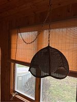 Full view of hanging rattan swag lamp with scalloped shade and metal chain.