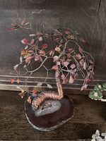 Large bonsai tree with red stone leaves and copper wire trunk on polished geode slice base