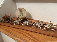 Full view of the Queen's carriage and Rockwell snow globe on a wooden shelf