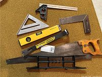 Overview of all tools including saw, levels, squares, and pry bar on a carpet