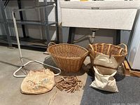 Photo of two woven baskets, canvas laundry bag, wooden clothes pins, and white adjustable drying rack near utility sink.