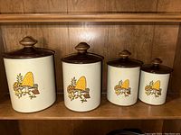 Full set of four vintage West Bend mushroom-themed kitchen canisters on wood shelf