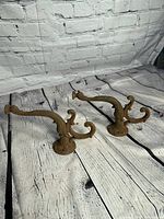 Pair of antique Victorian metal clothing hooks shaped like fish, showing full view with texture and patina.