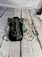 All six beaded necklaces displayed on a black necklace stand and white rustic wood background