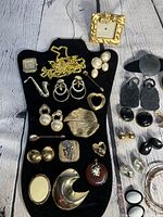 Photo showing full assortment of vintage Y2K costume jewelry items displayed on black velvet organizer and wooden table.