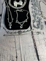 Close-up of rhinestone necklaces on black display showing details like teardrop pendant, link styles, and bow brooches.