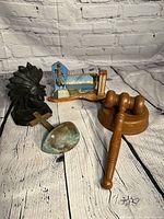Photo showing the wooden gavel and block, black Indian metal statue, anointing cross with basin, wooden bookend with beach scene and soldier statue