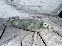 Side view showing the seal figurine's elongated body, smooth texture, and detailed head with eyes and nose.