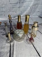 Perfume bottles arranged together on wooden surface with brick wall backdrop