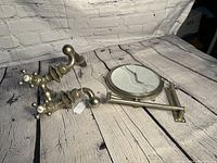 Mirror and two brass hot and cold faucets with patina on a rustic wooden surface against white brick.
