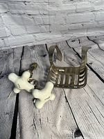 Photo showing a vintage metal soap dish and two white porcelain faucet knobs marked hot and cold in a rustic setting.