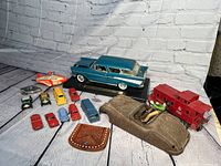 Overview of vintage Tootsie small cars, large blue Chevrolet Nomad model on display, red caboose train car, rustic metal car body, and small leather pouch.
