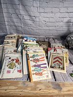 Lot of approximately 62 vintage sewing patterns displayed in stacks and piles with their printed envelopes showing various retro designs.