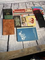 Full overview of lot with all books and collectibles arrayed on rustic white wooden surface.