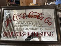 Full view of vintage Coca Cola advertising mirror showing text and decorative etched border on mirrored glass.