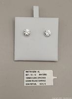 Pair of white gold earrings mounted on white display square with original tag showing item details: '10KWG CUBIC ZIRCONIA 6.5MM ROUND EARRING DOM REPUBL KOHL'S'