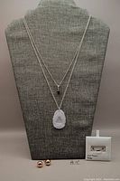 Full lot overview showing two necklaces on display bust and three pairs of earrings boxed/laid in front