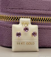 White jewelry mount showing round amethyst pendant and matching stud earrings stamped 14 KT GOLD