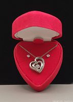 Full view of the sterling silver necklace with double heart pendant and matching stud earrings displayed in a red velvet heart-shaped box.