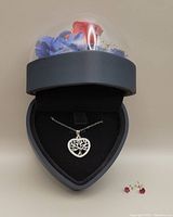 Image showing overall presentation of necklace in the heart-shaped box and ruby earrings outside.