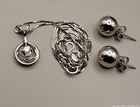 Set of white gold ball stud earrings, a white gold necklace with diamond pendant, and a purple velvet jewelry box for storage/travel.