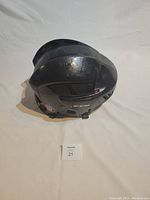 Side view of black CCM hockey helmet showing scuffed shell and adjustable fit system.