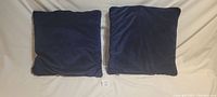 Two navy blue velvet cushions side by side on a white background, showing front view of cushions