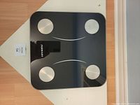 Top view of black digital scale with four silver circular sensors