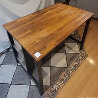 Angled view showing oak butcher block top and black frame legs