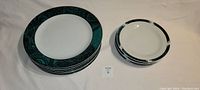 Stack of 6 dinner plates on the left and 6 side plates on the right, showing the green patterned trim around the edges.