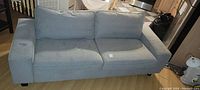 Front view of the Ikea Kivik sofa upholstered in grey fabric showing some discoloration and stains on cushions and armrests.