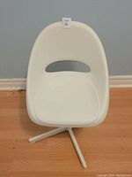 Front view of a youth student desk chair showing the molded white plastic seat and backrest with an oval cut-out, on a white metal tripod base.