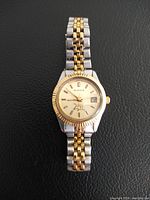 Front view showing the watch dial, Datejust style with gold-tone bezel and dual-tone metal bracelet.