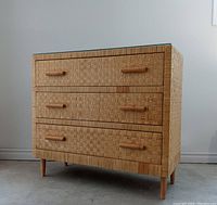 Front left three-quarter view of three-drawer cane dresser with glass top