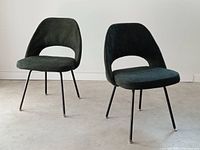Pair of chairs front three-quarter view on concrete floor against white wall