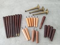 Top view showing the full assortment of furniture legs laid out, including wooden legs in various sizes and finishes and brass tapered legs.