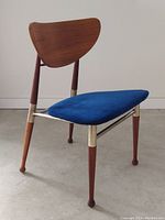 Front three-quarter view of chair showing walnut backrest, blue velvet seat and metal frame.