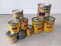 Photo shows nine cans of Minwax wood finishing products arranged in a pyramid stack. Multiple products including PolyShades, Wood Finish, and penetrating stains.