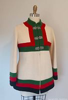 Front view of Nordic style vintage wool coat on mannequin showing color block design in cream, red, green, and black with clasp and zipper closure.